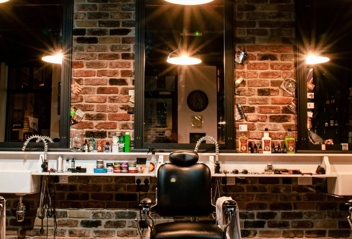 The row of barber's chairs and the mirrors along the brick wall, under the shop's pendant lamps